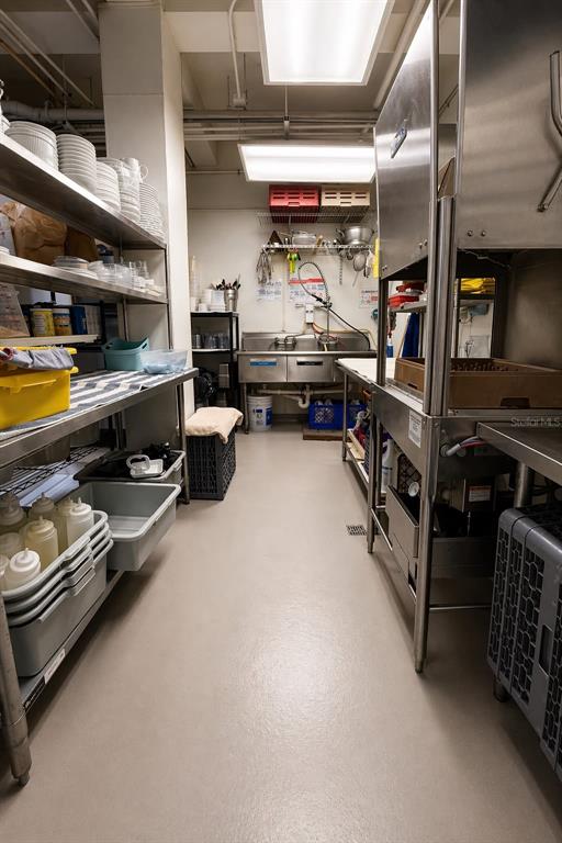 A commercial kitchen features stainless steel equipment, open shelving with dishware, and a utility sink — 619 CALLE CERRA, SAN JUAN, PR