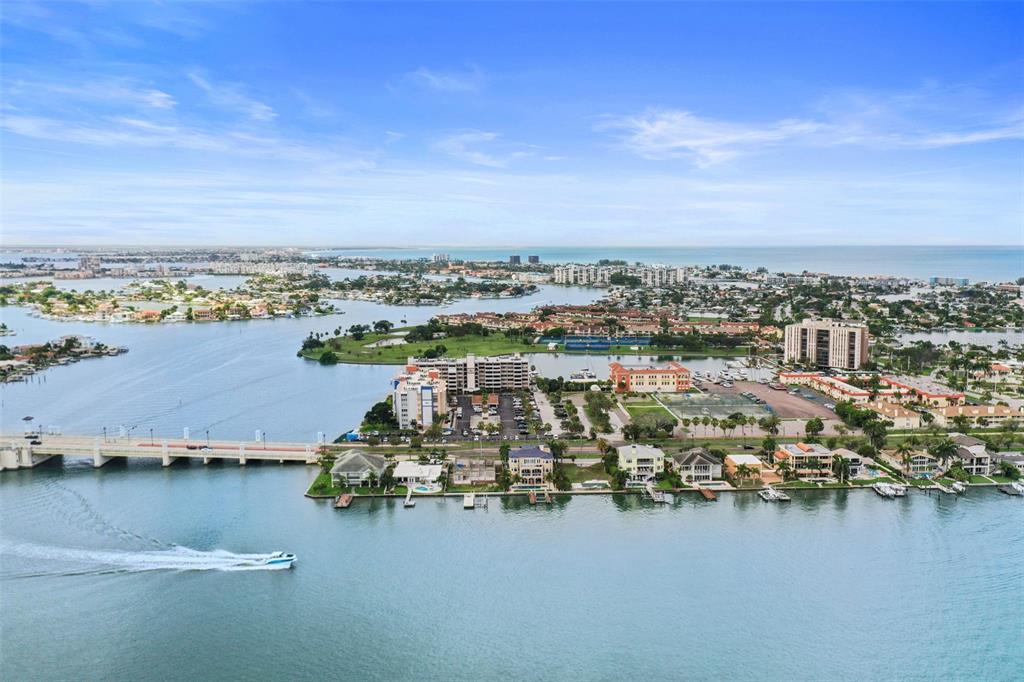 An aerial view of a waterfront neighborhood with a bridge, boat, and residential buildings — 500 TREASURE ISLAND CAUSEWAY UNIT 610, TREASURE ISLAND, FL