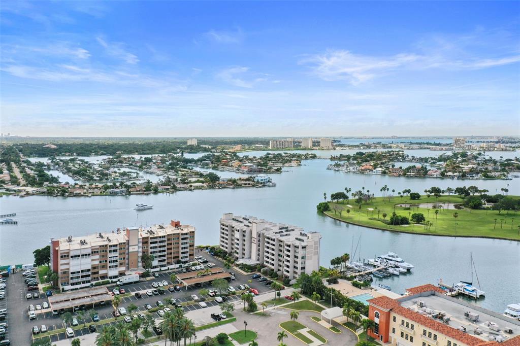 An aerial view shows waterfront apartment buildings, a parking lot, and a marina — 500 TREASURE ISLAND CAUSEWAY UNIT 610, TREASURE ISLAND, FL