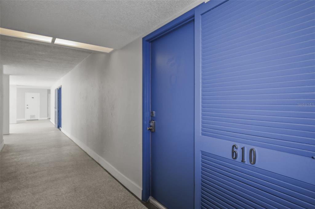 A blue door with the number 610 is located in a carpeted apartment building hallway — 500 TREASURE ISLAND CAUSEWAY UNIT 610, TREASURE ISLAND, FL