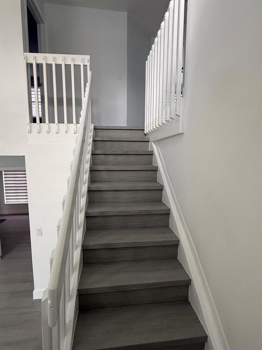 A staircase with gray wood-look treads and white railings leads to an upper landing — 4415 SW 72nd Terrace, Davie FL 33314, DAVIE, FL