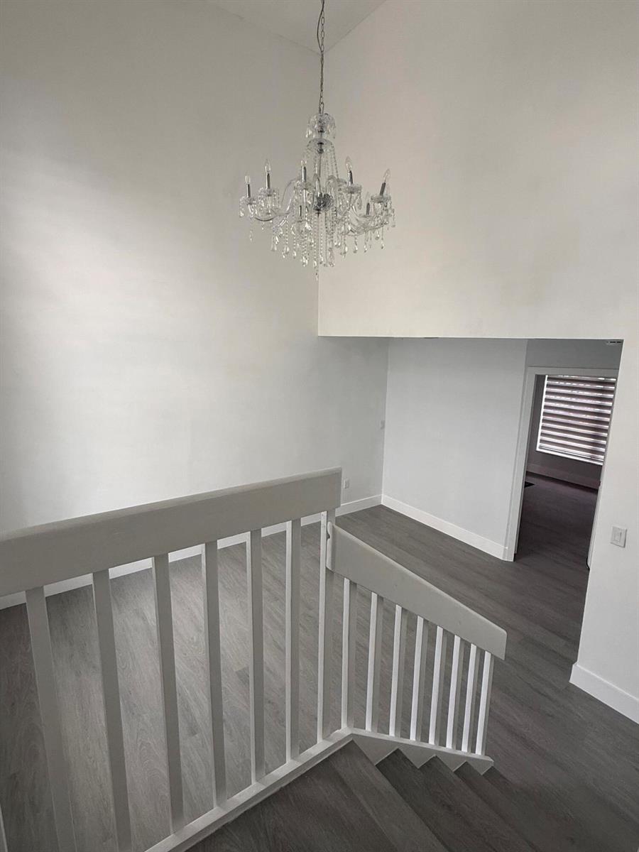 A staircase with white railings leads to a landing featuring a crystal chandelier — 4415 SW 72nd Terrace, Davie FL 33314, DAVIE, FL