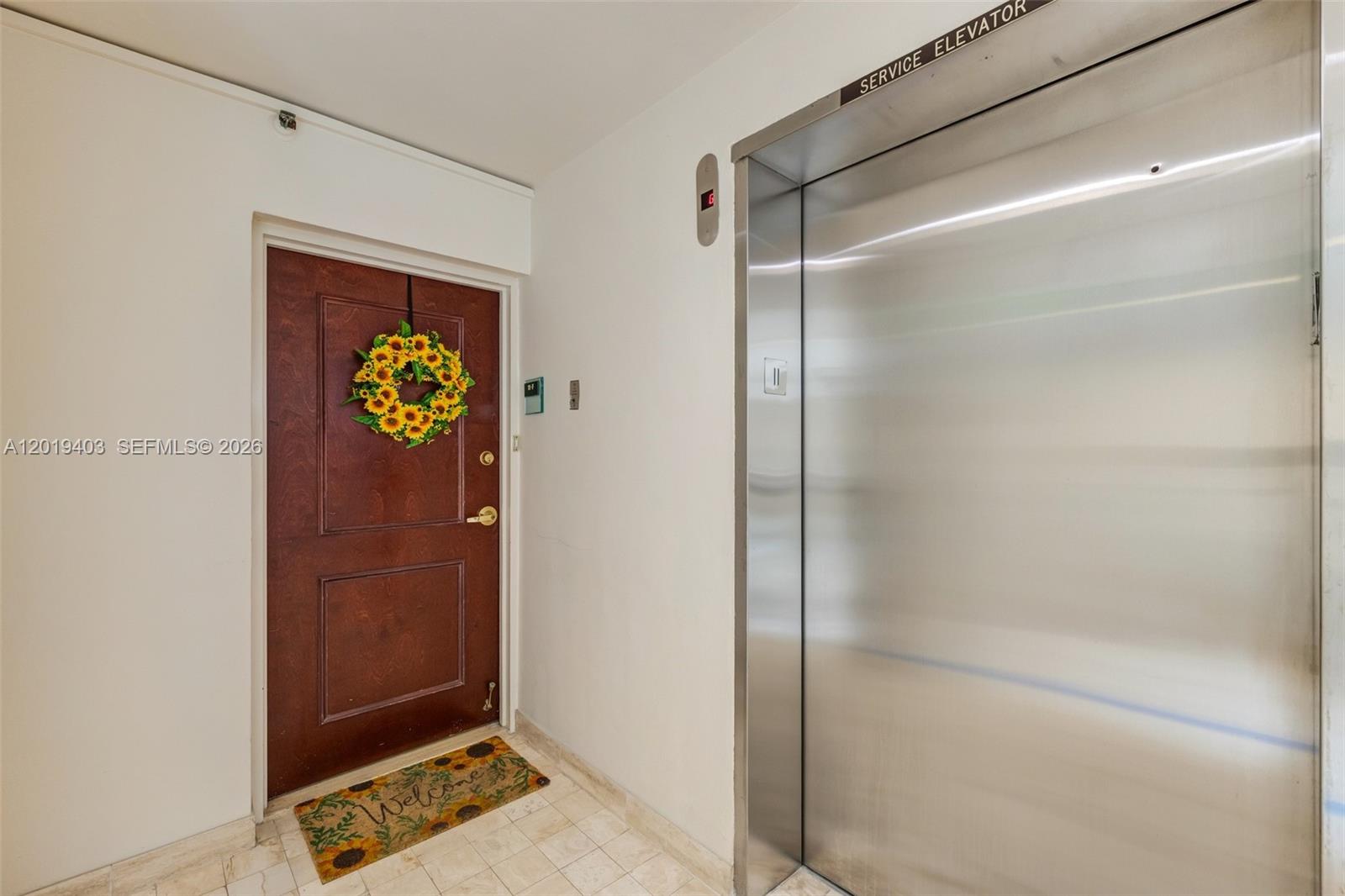 A brown door with a sunflower wreath sits next to a stainless steel service elevator — 2843 S Bayshore Dr # 11F, Miami FL 33133, MIAMI, FL