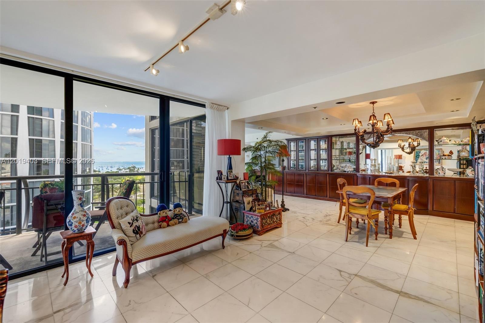 A living and dining area with marble floors, a balcony, and a built-in wooden cabinet — 2843 S Bayshore Dr # 11F, Miami FL 33133, MIAMI, FL