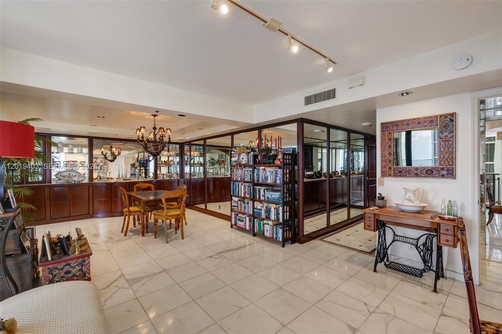 A living and dining area features marble floors, mirrored walls, and a vintage sewing machine table — 2843 S Bayshore Dr # 11F, Miami FL 33133, MIAMI, FL