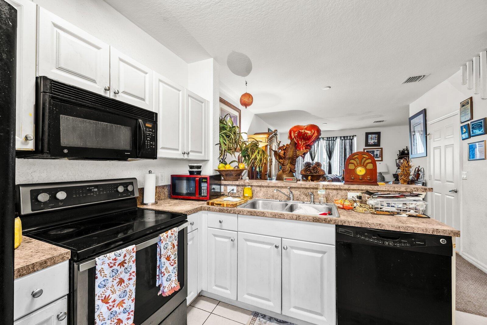 A kitchen features white cabinets, black appliances, a double sink, and a laminate countertop — 3529 Sonoma Drive, Riviera Beach FL 33404, RIVIERA BEACH, FL