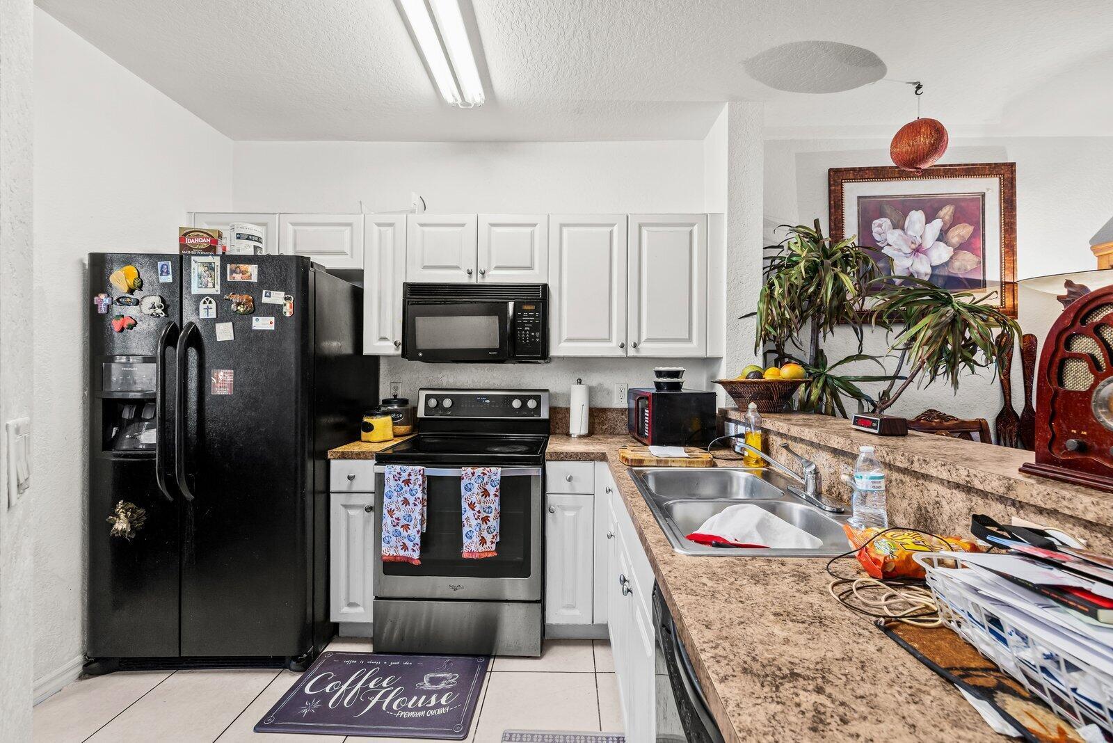 A kitchen features white cabinets, a black refrigerator, a stainless steel stove, and laminate countertops — 3529 Sonoma Drive, Riviera Beach FL 33404, RIVIERA BEACH, FL