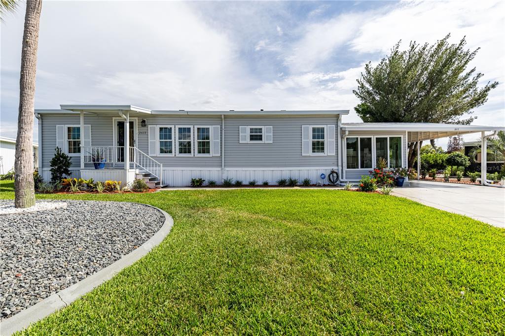 A single-story manufactured home with light gray siding, a front porch, and a carport — 2611 VINDALE ROAD, TAVARES, FL
