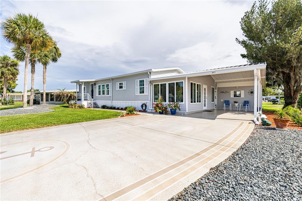 A single-story manufactured home with light gray siding, a carport, and a concrete driveway — 2611 VINDALE ROAD, TAVARES, FL