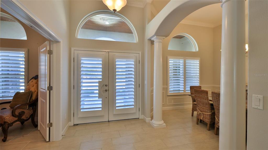 A bright entryway features double doors, arched windows, tile flooring, and a decorative column — 2904 PALMA LANE, NEW SMYRNA BEACH, FL