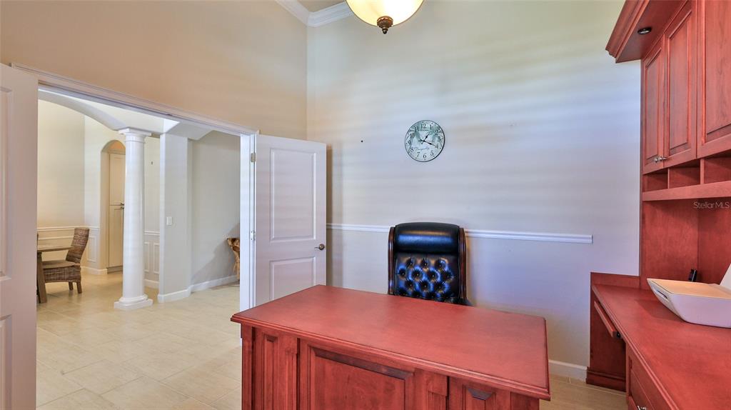 A home office features a wooden desk, a leather chair, and built-in cabinetry — 2904 PALMA LANE, NEW SMYRNA BEACH, FL