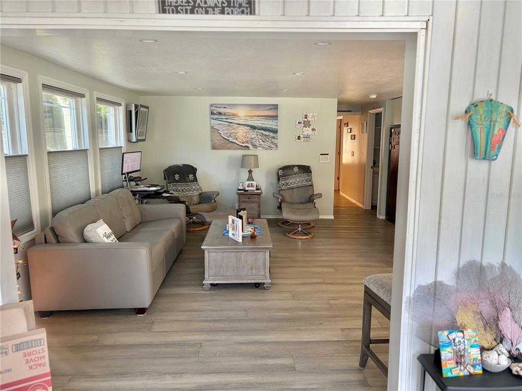 A living room features light wood flooring, a gray sofa, two recliners, and a coffee table — 121 TAMARISK WAY, LEESBURG, FL