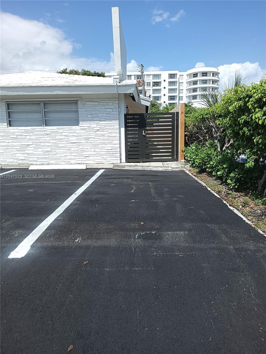 A white stone building exterior features a black horizontal-slat gate and a paved parking space — FORT LAUDERDALE, FL