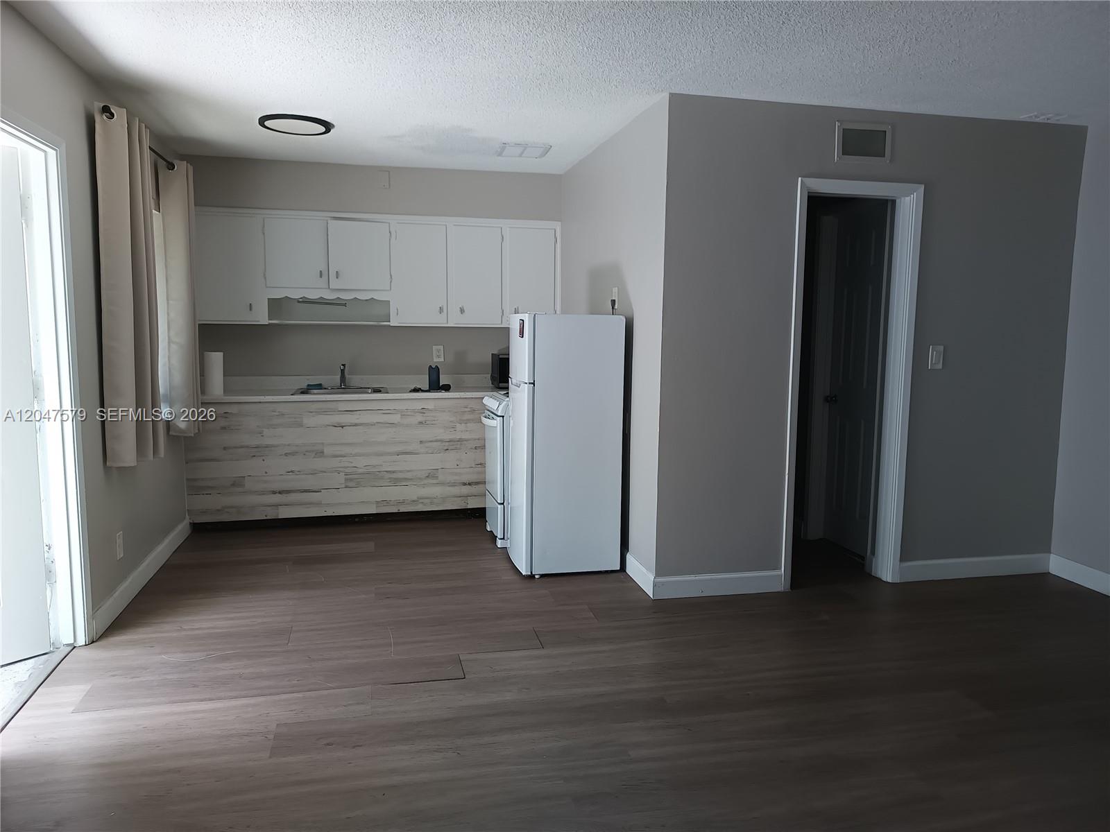 A kitchen with white cabinets, a white refrigerator, and wood-look flooring — FORT LAUDERDALE, FL