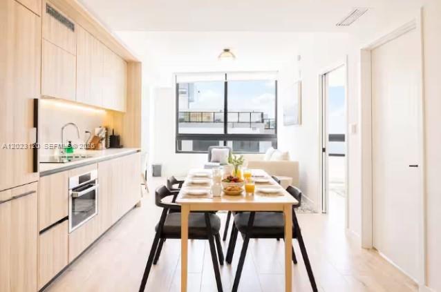 A modern kitchen and dining area with light wood cabinetry and a large window — 225 N Miami Ave # 3204, Miami FL 33128, MIAMI, FL