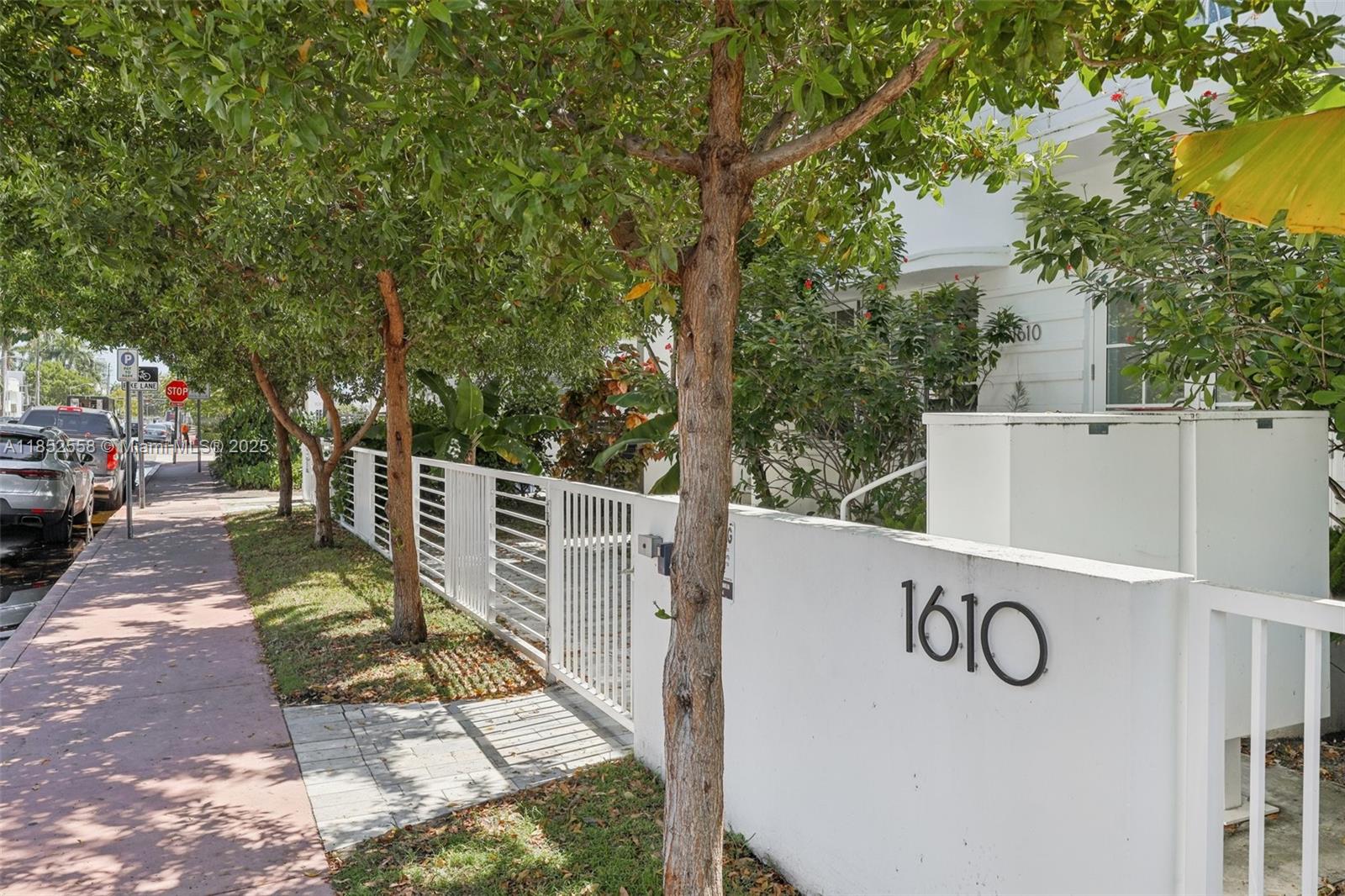 A white wall with the number 1610 stands beside a sidewalk and a gated entrance — 1610 Euclid Ave # B101, Miami Beach FL 33139, MIAMI BEACH, FL