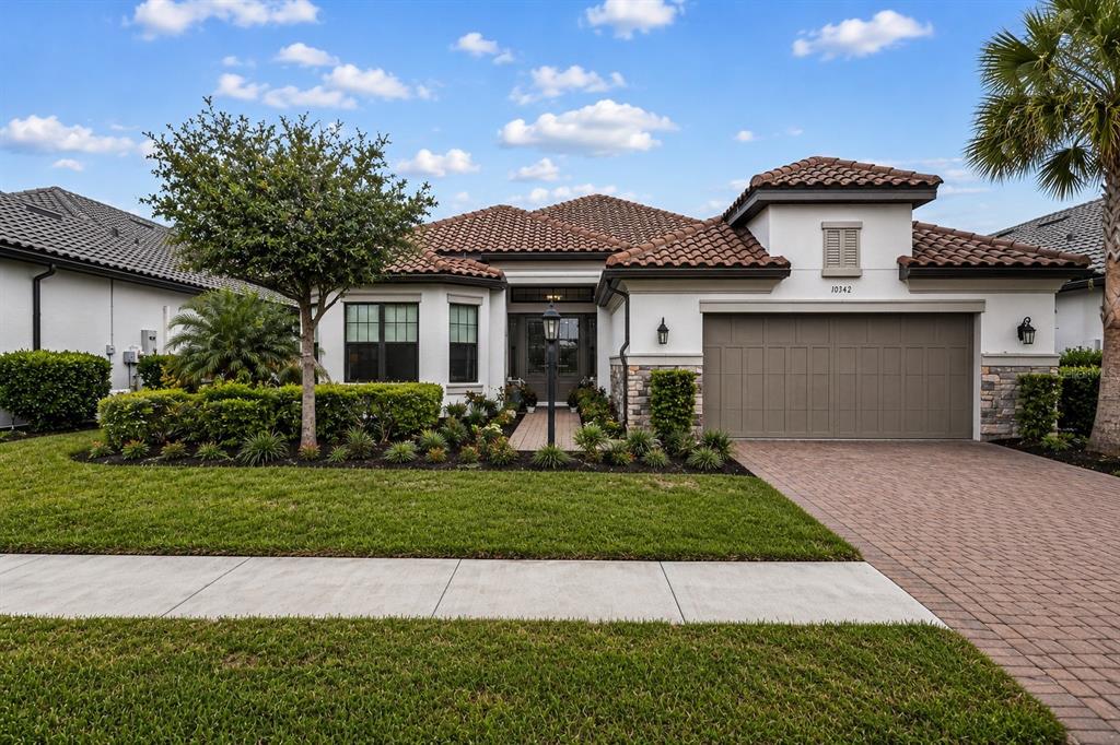 A single-story house with a tiled roof, a two-car garage, and a landscaped front yard — 10342 MORNING MIST LANE, SARASOTA, FL