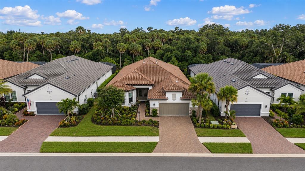 An aerial view shows three suburban houses with tiled roofs and paved driveways — 10342 MORNING MIST LANE, SARASOTA, FL