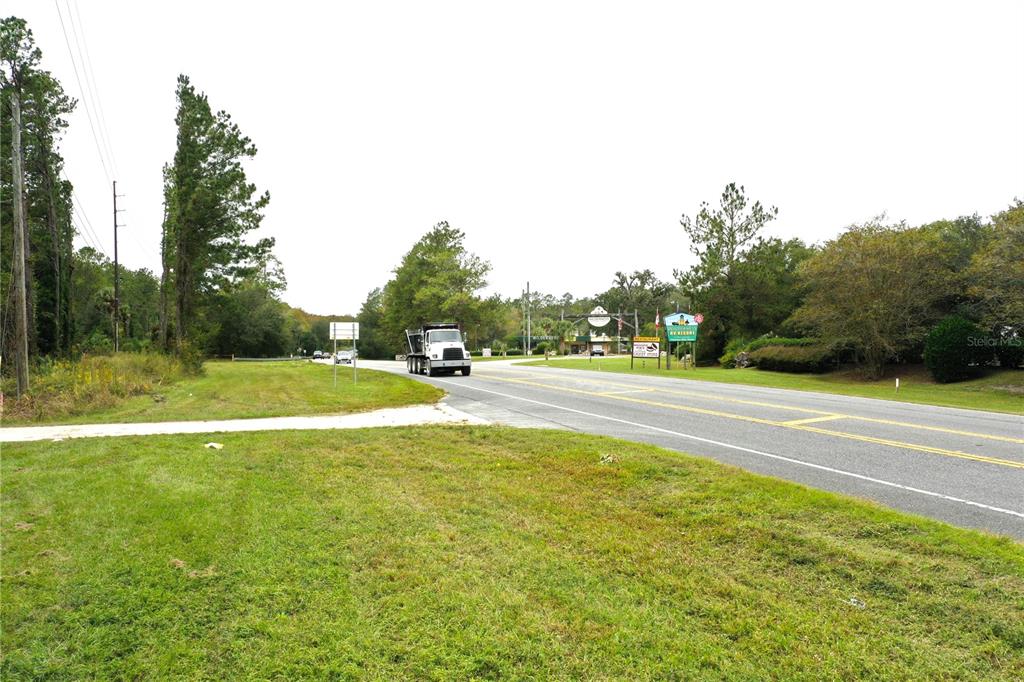 A white dump truck drives on a paved road past a resort entrance sign — TBD E HIGHWAY 40, SILVER SPRINGS, FL