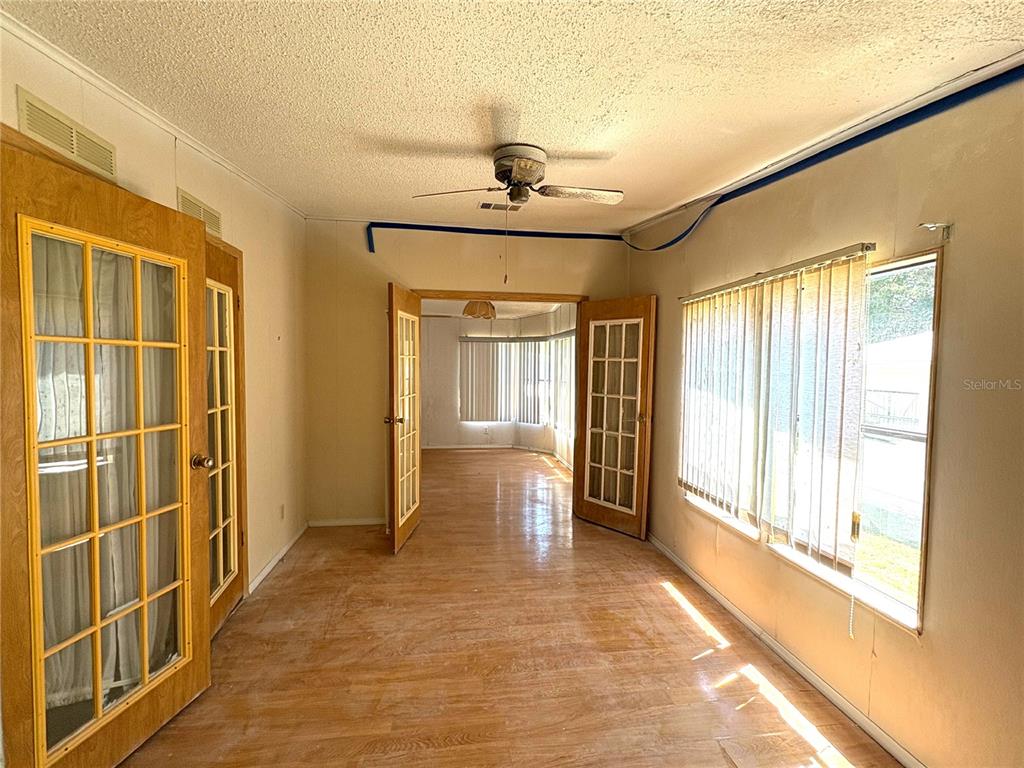 A sunroom with wood-look flooring, a ceiling fan, and French doors leading to another room — 25034 BETTON HILL, LEESBURG, FL