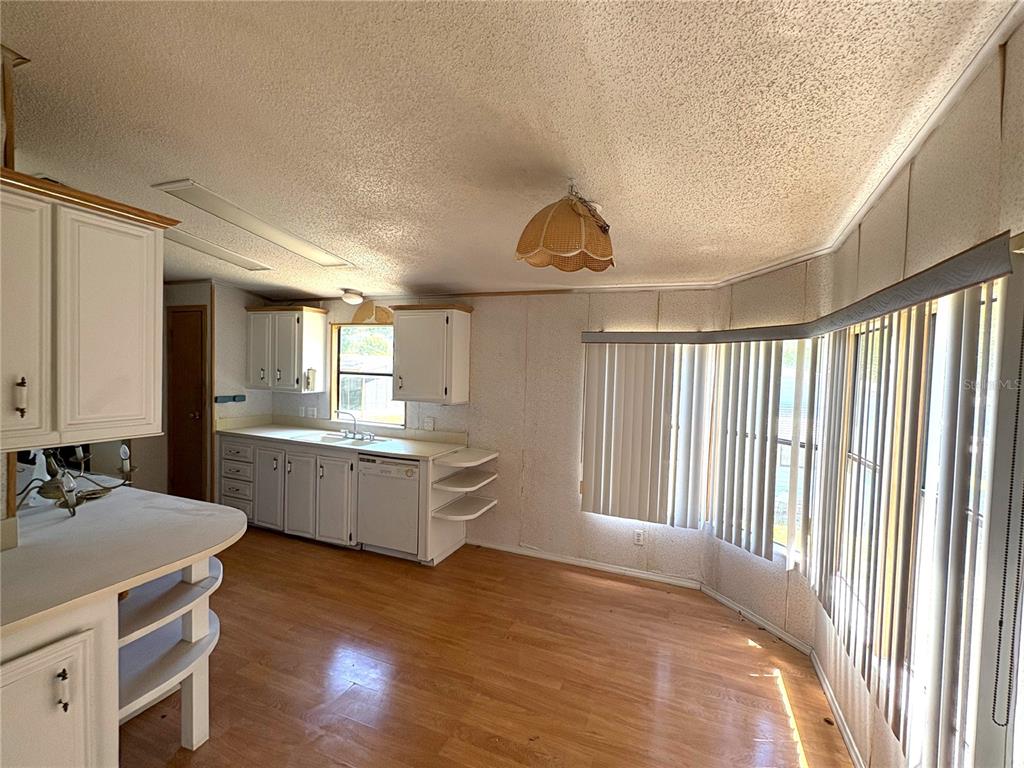 A kitchen with white cabinets, wood-look flooring, and a large bay window with vertical blinds — 25034 BETTON HILL, LEESBURG, FL