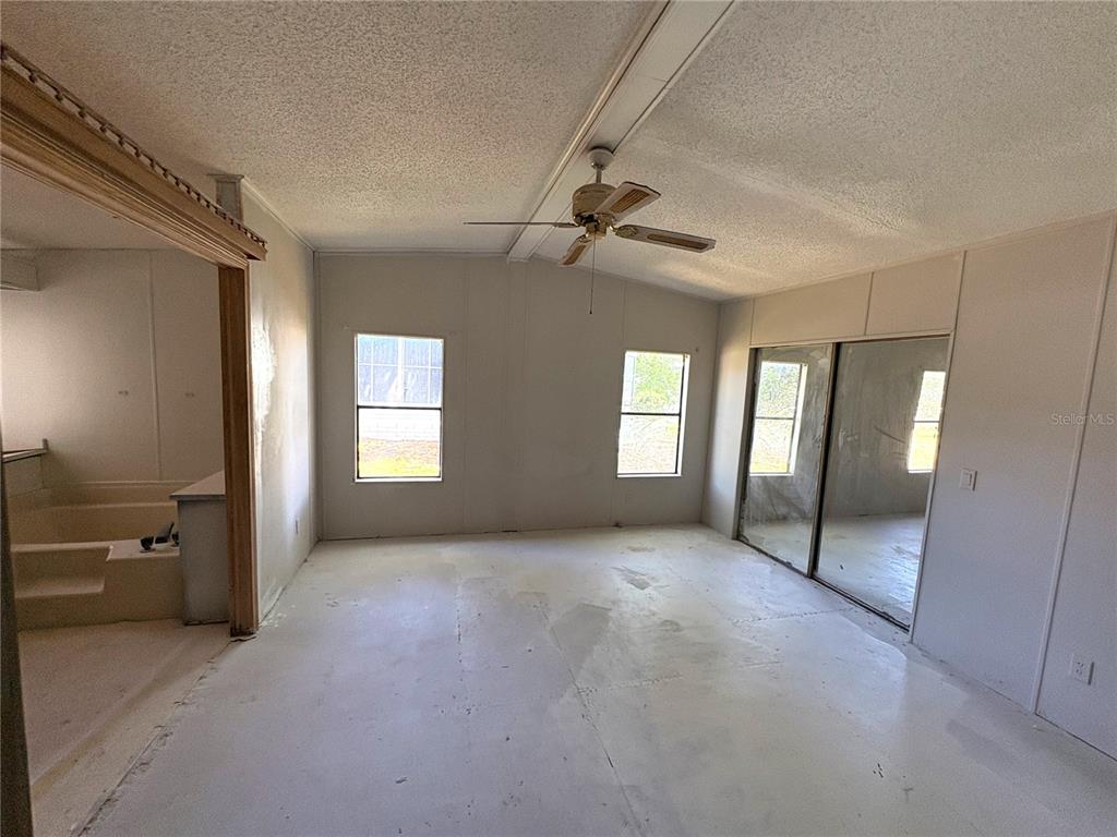 An unfinished room with a ceiling fan, sliding glass doors, and an adjacent bathroom area — 25034 BETTON HILL, LEESBURG, FL