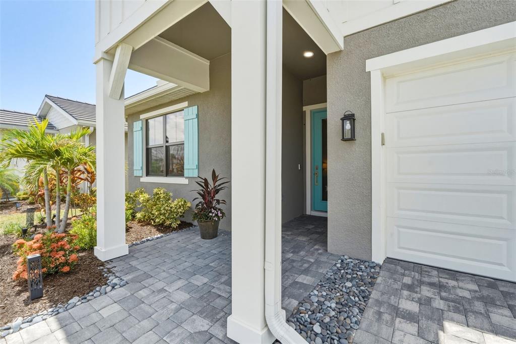 A paved walkway leads to a covered entryway with a teal door and white columns — 18857 DAYBREAK DRIVE, VENICE, FL