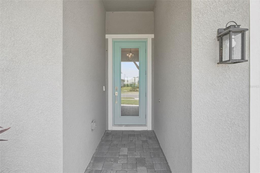 A light blue front door with a glass insert sits at the end of a walkway — 18857 DAYBREAK DRIVE, VENICE, FL