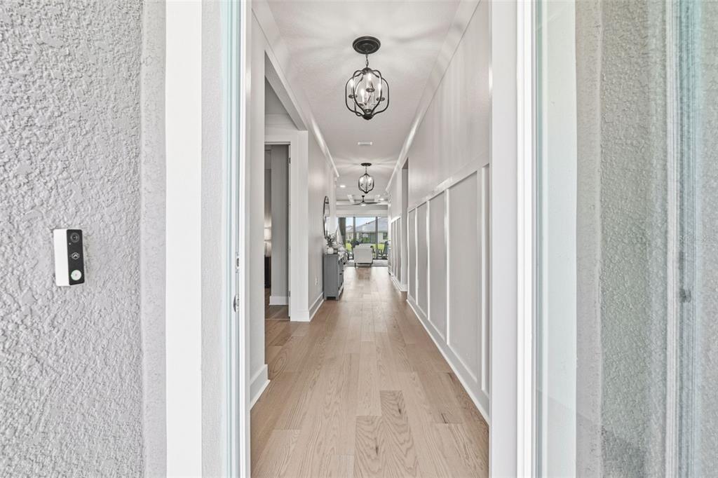 A view through a doorway into a hallway with light wood floors and wall molding — 18857 DAYBREAK DRIVE, VENICE, FL