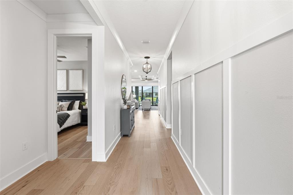 A bright hallway with light wood floors and white board-and-batten wall trim leads forward — 18857 DAYBREAK DRIVE, VENICE, FL