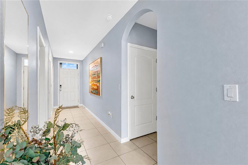 A bright entryway features light blue walls, tile flooring, an arched doorway, and a front door — 1795 PARTIN TERRACE ROAD S, KISSIMMEE, FL