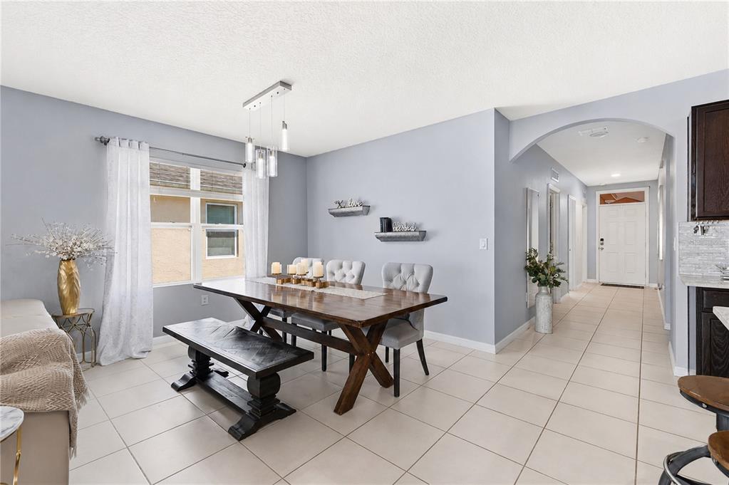A dining room features a wooden table with a bench and chairs under pendant lighting — 1795 PARTIN TERRACE ROAD S, KISSIMMEE, FL
