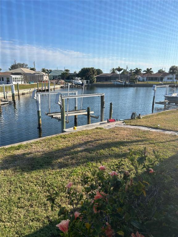 A view of a canal with a boat lift from a grassy backyard — 1727 BOCA RATON COURT, PUNTA GORDA, FL