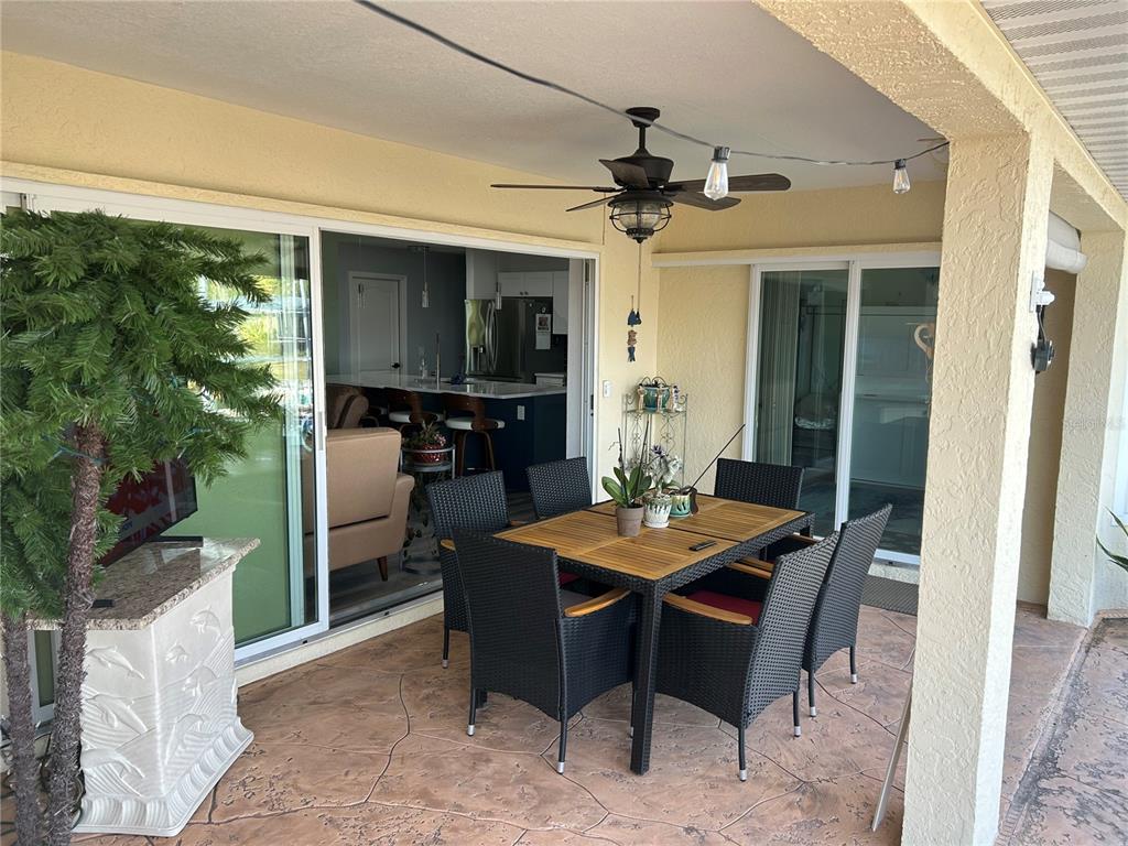 A covered patio features a dining set, a ceiling fan, and sliding glass doors — 1727 BOCA RATON COURT, PUNTA GORDA, FL