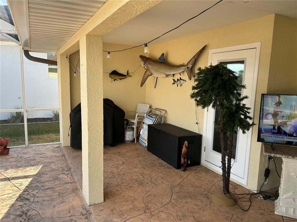 A covered patio features a concrete floor, a shark wall mount, and a grill cover — 1727 BOCA RATON COURT, PUNTA GORDA, FL