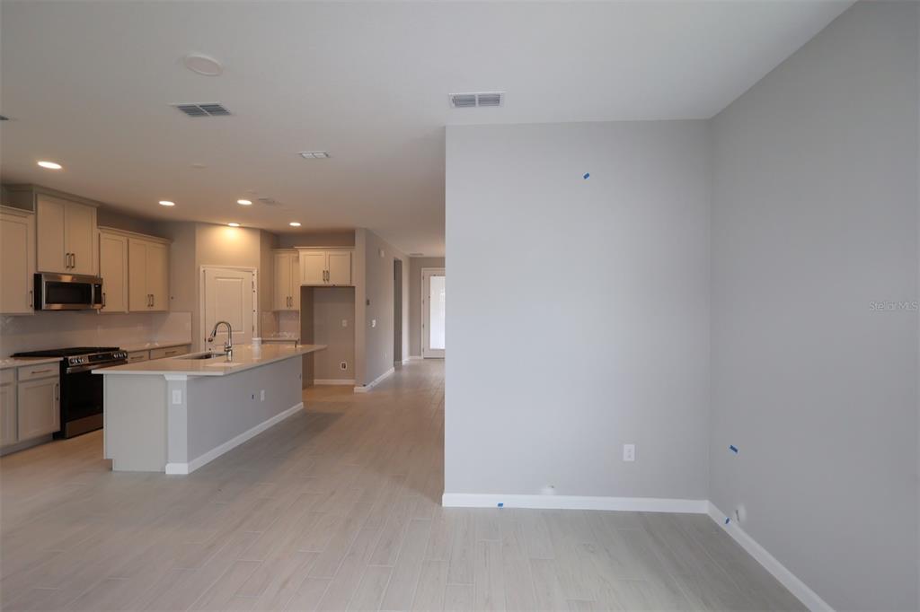 A kitchen with light-colored cabinets and a center island opens to a gray-walled living area — 1347 LUMPINI STREET, ST CLOUD, FL