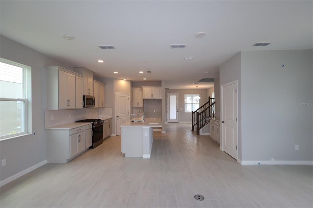 A kitchen with light gray cabinets, a central island, and tile flooring opens to a hallway — 1347 LUMPINI STREET, ST CLOUD, FL