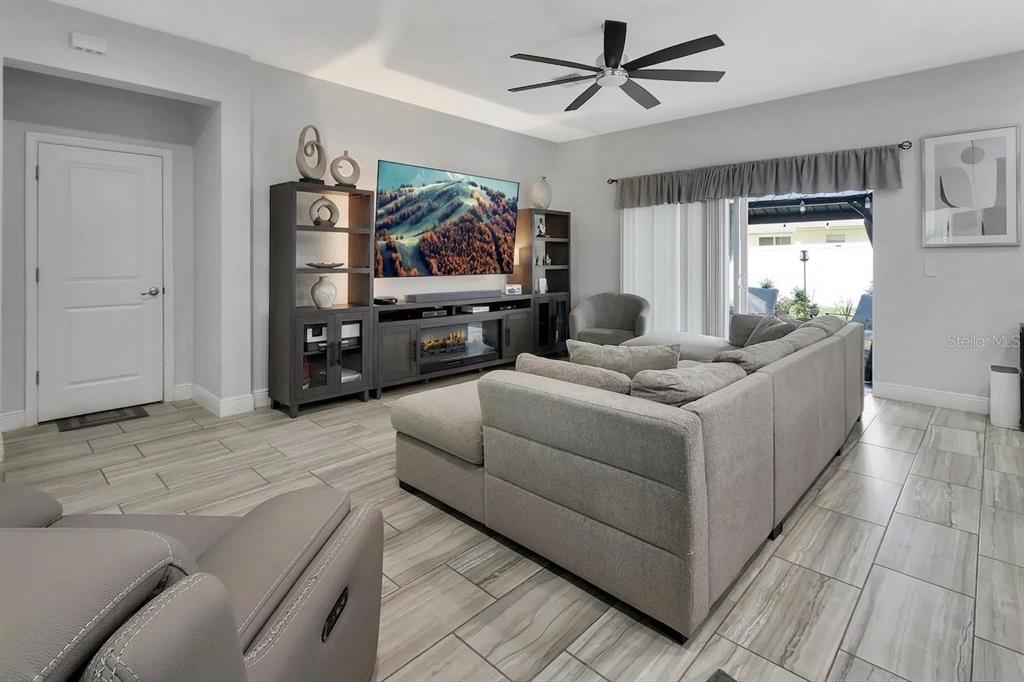 A living room features a large sectional sofa, media console with fireplace, and tile flooring — 1580 13TH STREET, ORANGE CITY, FL