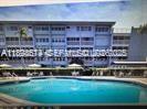 A swimming pool sits in front of a multi-story blue apartment building — 215 SE 3rd Ave # 107A, Hallandale Beach FL 33009, HALLANDALE BEACH, FL