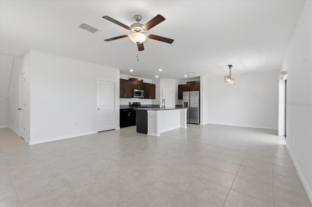 An open-concept kitchen and living area featuring dark cabinetry, a central island, and tile flooring — 5224 WHITE CHICORY DRIVE, APOLLO BEACH, FL