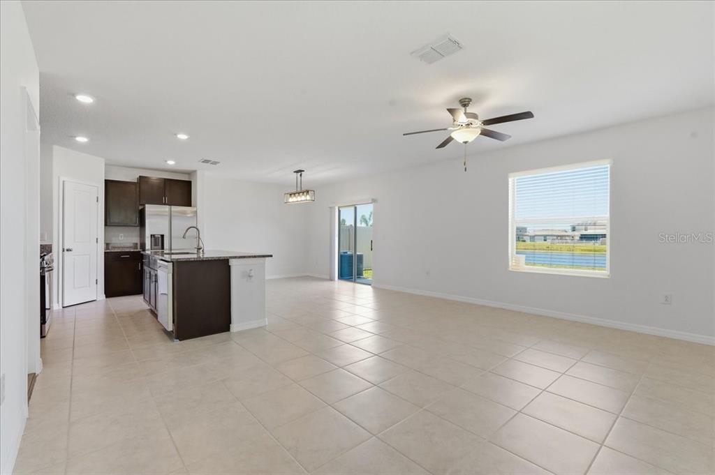 An open-concept kitchen and living area with tile flooring, dark cabinetry, and a ceiling fan — 5224 WHITE CHICORY DRIVE, APOLLO BEACH, FL
