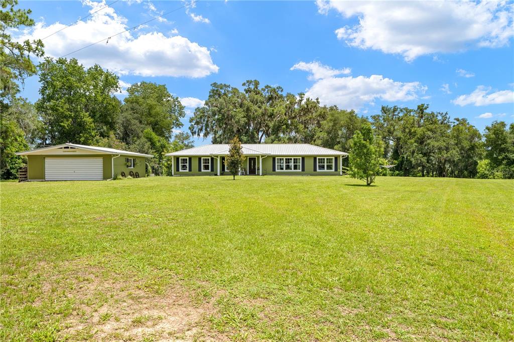 A green single-story house with a detached garage sits on a large, grassy lot — 23439 CROOM ROAD, BROOKSVILLE, FL