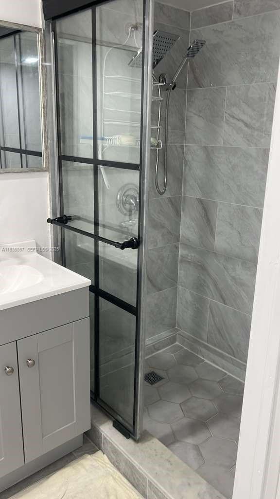 A bathroom features a gray vanity, a walk-in shower with black-framed glass, and tiled walls — 1911 SW 87th Ave, Davie FL 33324, DAVIE, FL