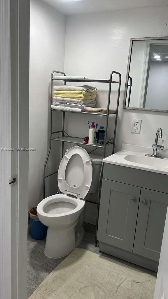 A bathroom features a toilet, a grey vanity with a sink, and a metal shelving unit — 1911 SW 87th Ave, Davie FL 33324, DAVIE, FL