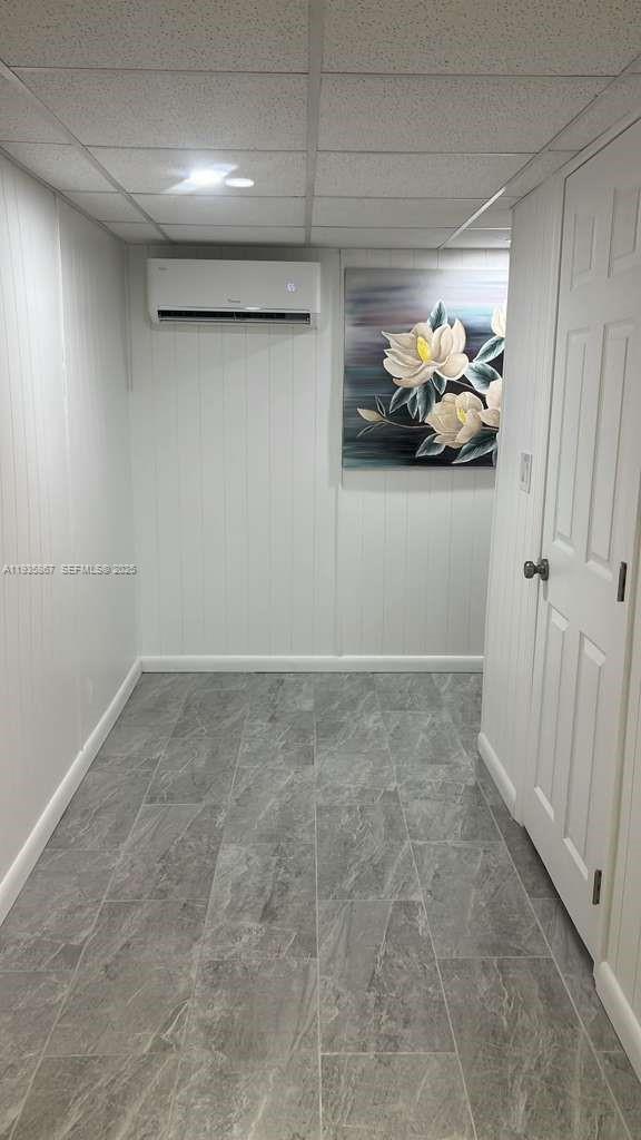 A small room features gray tile flooring, white paneled walls, a wall-mounted air conditioner, and artwork — 1911 SW 87th Ave, Davie FL 33324, DAVIE, FL