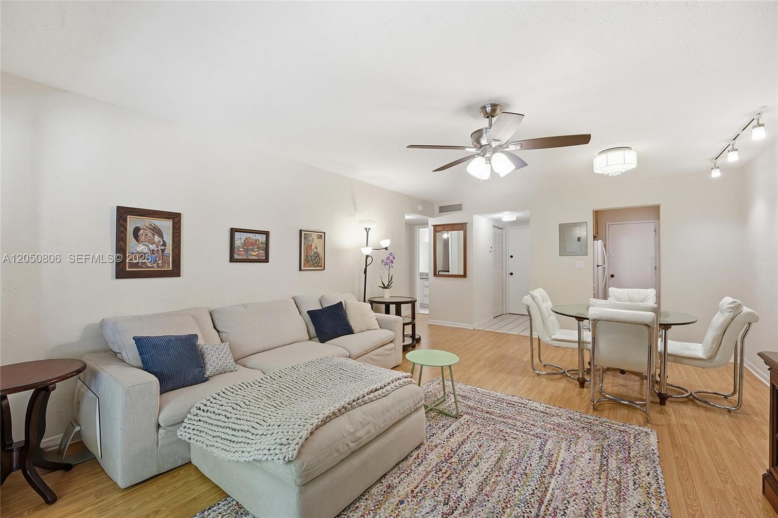 A living room features a sectional sofa, a dining set, and light wood flooring — 1205 Mariposa Ave # 403, Coral Gables FL 33146, CORAL GABLES, FL