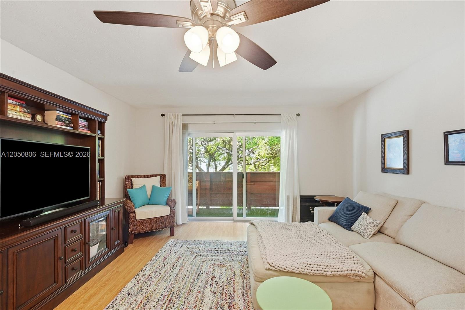 A living room features a sectional sofa, a wooden media console, and a sliding door — 1205 Mariposa Ave # 403, Coral Gables FL 33146, CORAL GABLES, FL