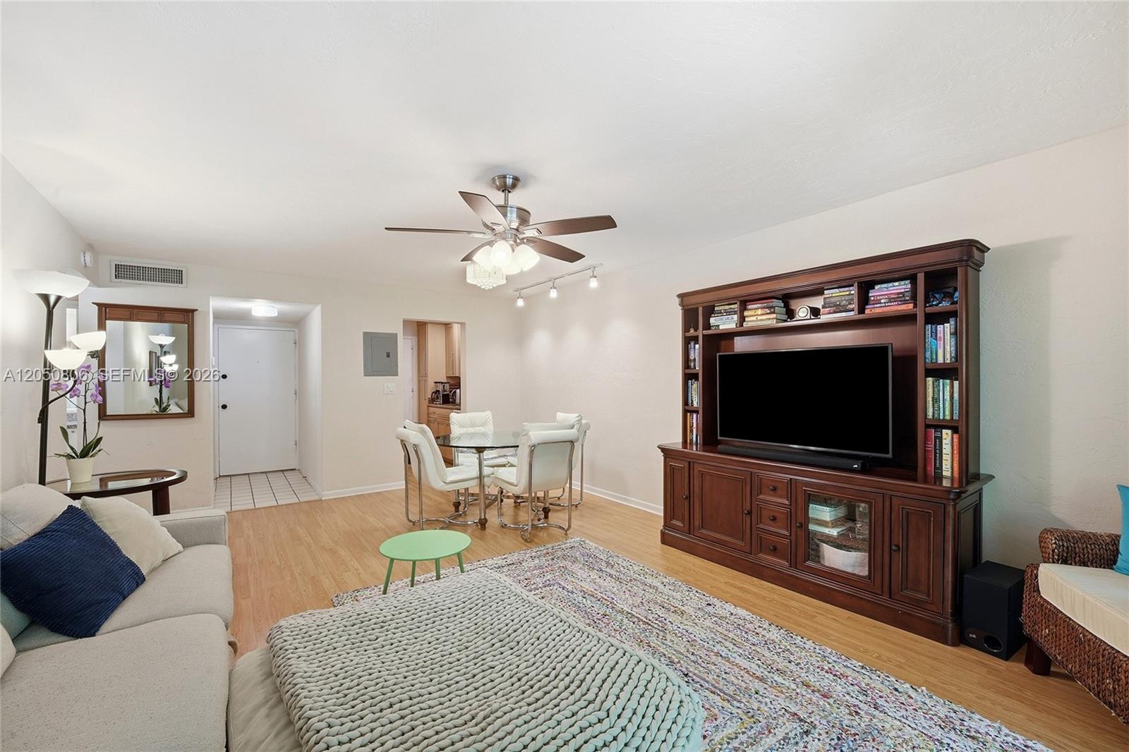 A living room features a wooden entertainment center, a dining set, and light wood flooring — 1205 Mariposa Ave # 403, Coral Gables FL 33146, CORAL GABLES, FL