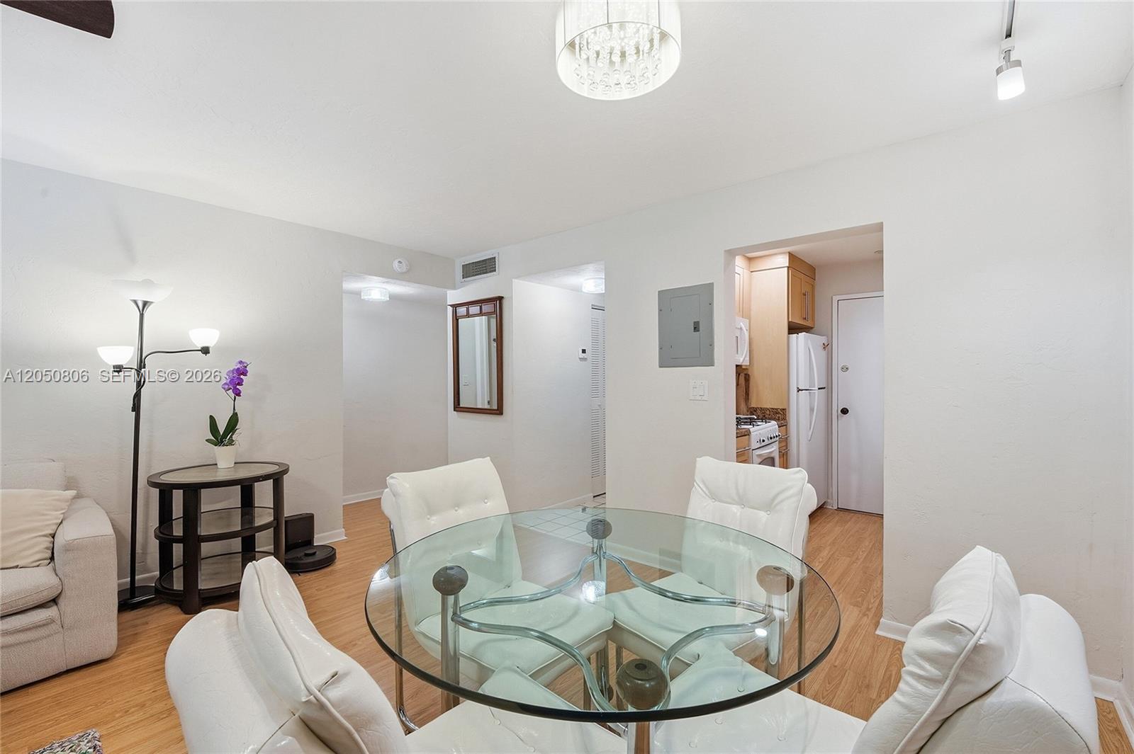 A dining area features a glass table, white chairs, and an adjacent kitchen entrance — 1205 Mariposa Ave # 403, Coral Gables FL 33146, CORAL GABLES, FL