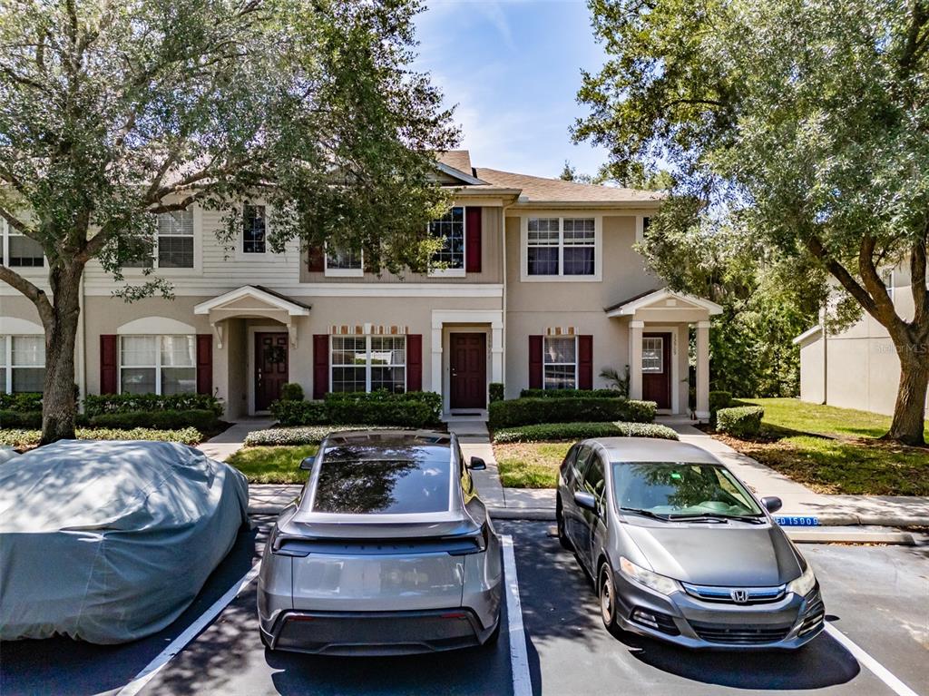 A row of townhouses with beige siding, red shutters, and parked cars in the foreground — 15911 FISHHAWK VIEW DRIVE, LITHIA, FL